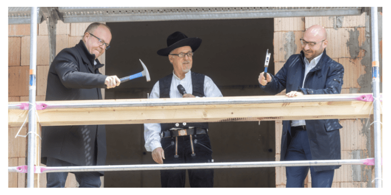 Startseite: Richtfest mit Handwerkern und Bauarbeitern auf Gerüst.